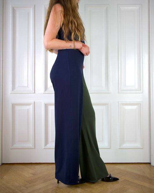 Woman wearing a two-tone long wide pants dress with a high waist and a matching blue top, standing against a white paneled wall.