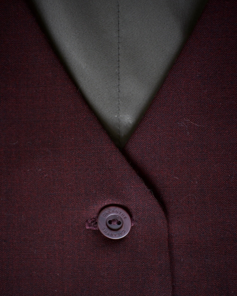Close-up of a button on a maroon fabric with a green lining.